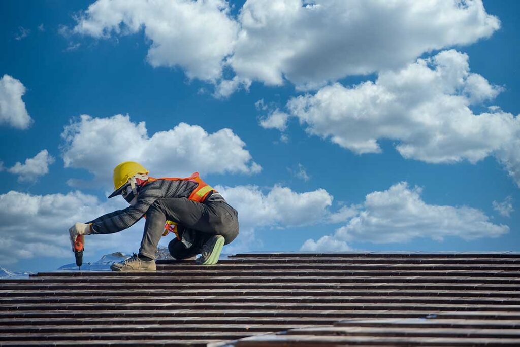 A residential roof displaying metal panels, slate tiles, and asphalt shingles under seasonal weather conditions.